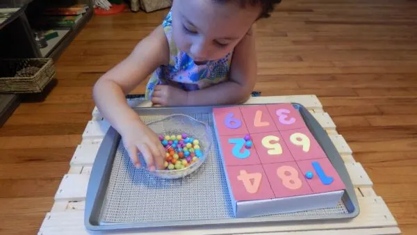 child pushing push pins into cardboard for 1:1 correspondence activity.