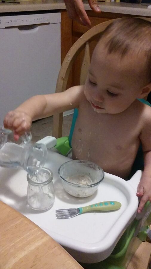child pouring water into glass.
