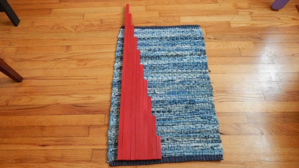 DIY Montessori Red Rods lined up by size on rug.