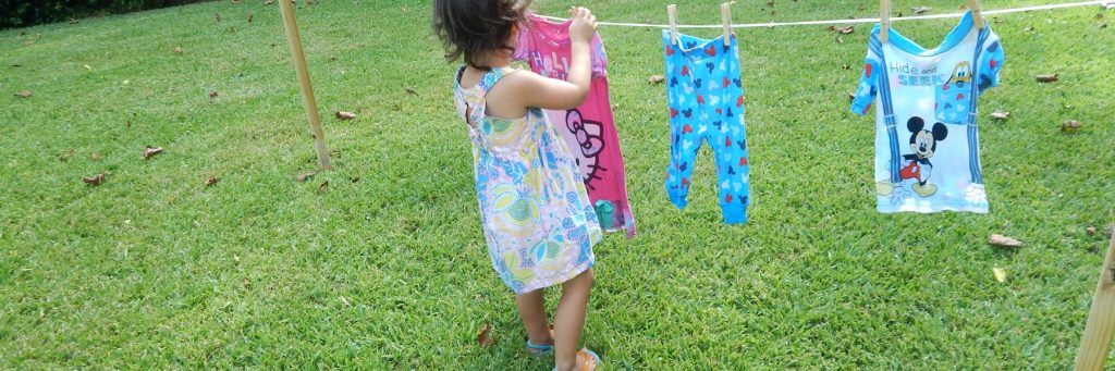 child hanging clothes on child size clothes line.