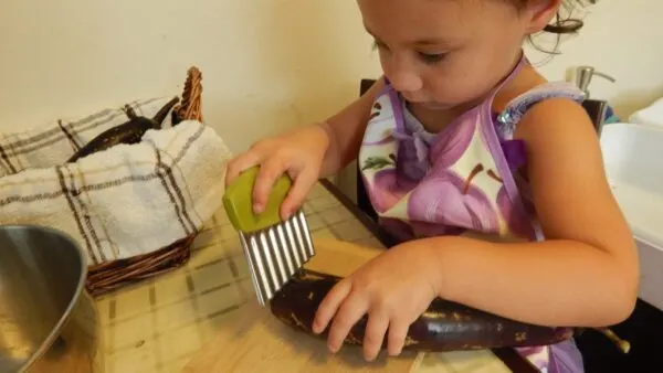 child chopping eggplant, a montessori practical life activity.