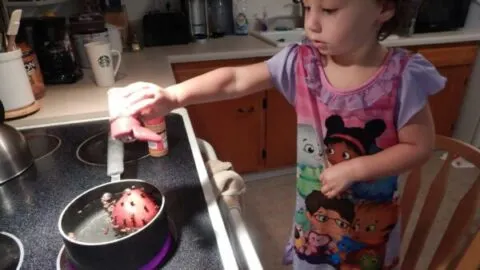 child pouring spices into pot