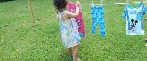 child hanging clothes on child size clothes line.