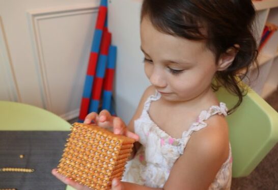 Child holding Golden Bead Material during the math Montessori sensitive periods.