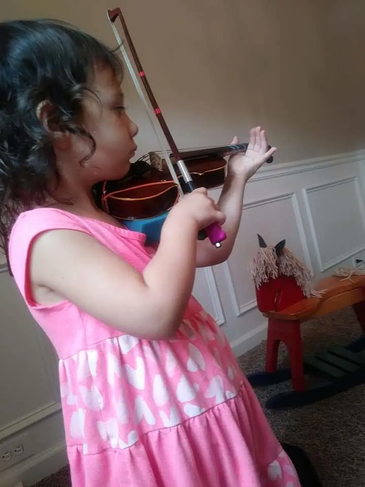 Child playing a violin during the sensitive period for music.