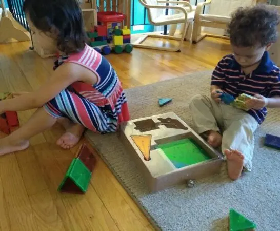 2 young children playing with magna-tiles.