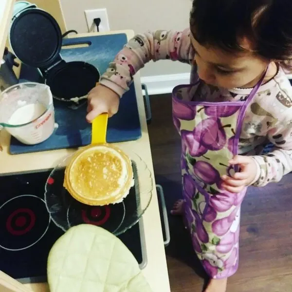 child cooking real food on ikea montessori play kitchen. Adapting a play kitchen is one way how to get started with Montessori.