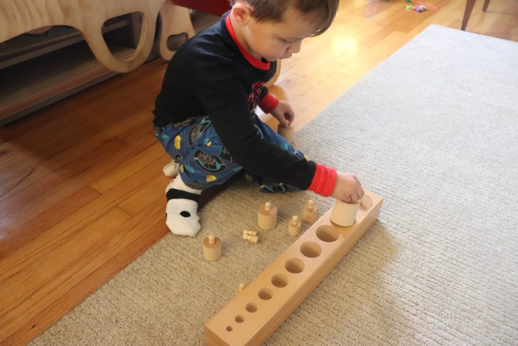 boy using Montessori Knobbed cylinders.
