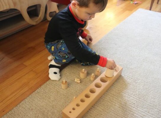 boy using Montessori Knobbed cylinders.