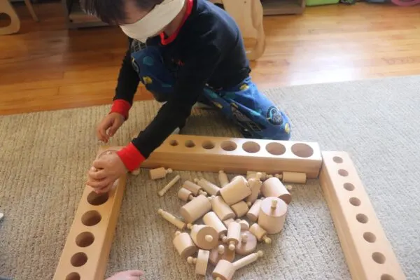 young boy working blindfolded working with the Montessori Knobbed Cylinders