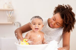 Mother bathing baby. A relaxing bath is where gentle parenting and sleep training meet.
