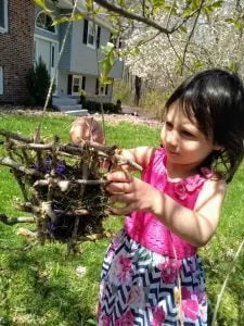 Child putting leaves into DIY Nesting Material Box.