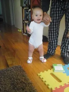 baby taking first assisted steps, proud of herself. An example of why good job is harmful