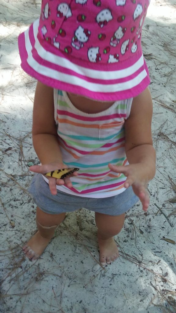 child holding butterfly, exploring on her own, showing the importance of free play.