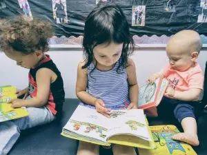 3 young children reading, in Montessori writing before reading is taught.