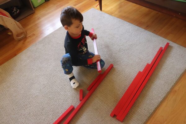 4 year old placing the Montessori Red Rods in order.