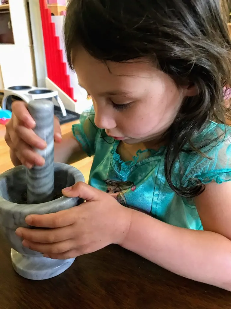 child grinding herbs for practical life activities.