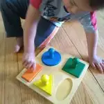 2 year old putting knobbed puzzle together, puzzles are good for fine motor skills and make great Montessori gifts.