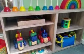 how to organize playroom: bookshelf with rainbow stacker, puzzle, wooden train, sound bells.