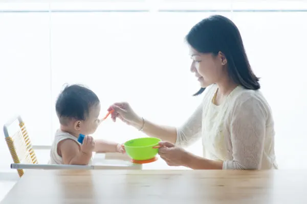 Mother giving baby purees.