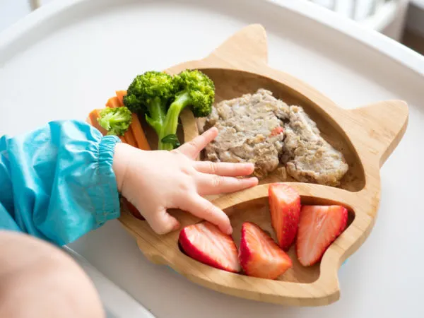 Baby, reaching for food on tray. Baby led weaning.