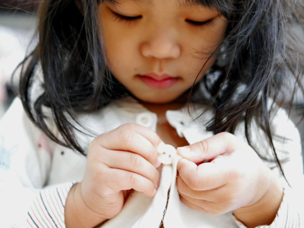 Young child, trying to button sweater.