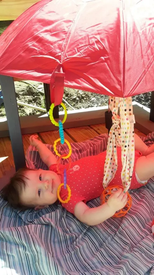 baby outside under umbrella, a gross motor activity