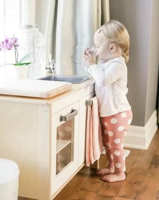 child drinking from glass at Montessori at home ikea kitchen.