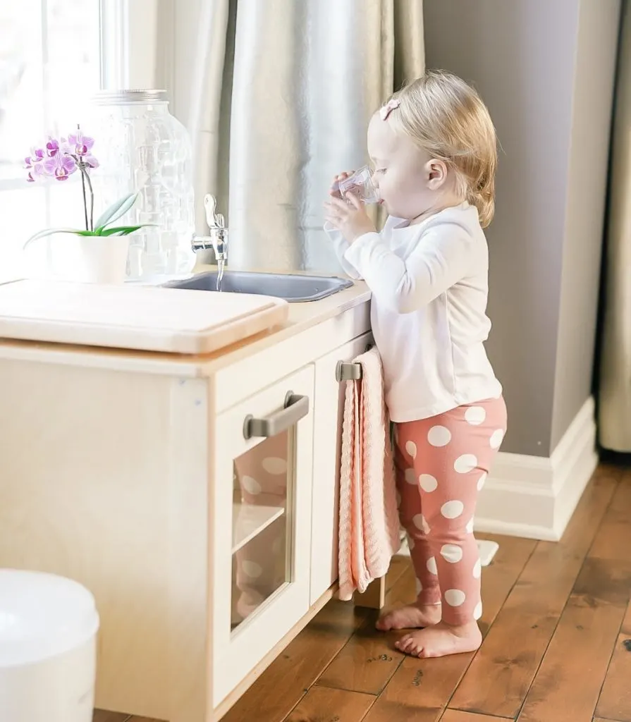 child drinking from glass at Montessori ikea kitchen.