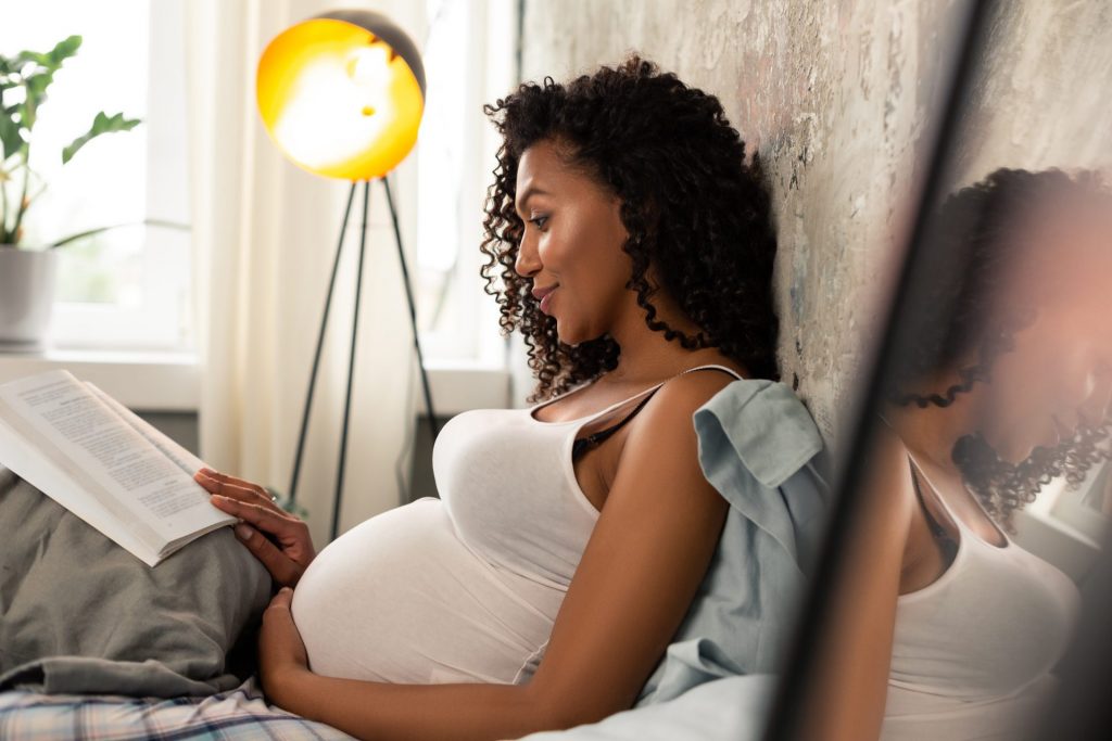 Pregnant women with a Montessori book to read