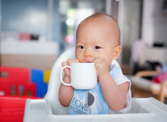 Baby drinking from glass instead of plastic mug.