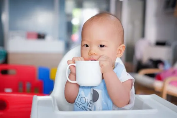 Baby drinking from glass mug