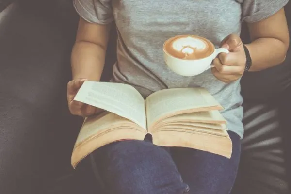 What Montessori Book Should You REad First? image of woman reading Montessori book with coffee.