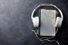 Headphones covering book to represent audiobook. Audiobooks and vocabulary.