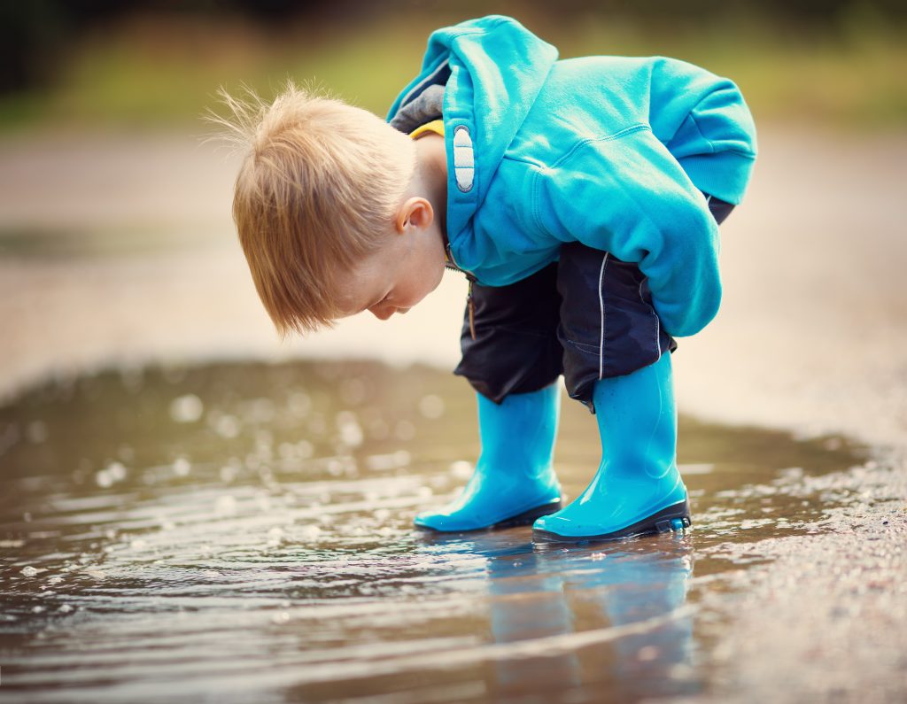a boy using his Absorbent Mind, exploring a puddle, during a sub- plane of development.