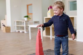 Boy building Montessori Pink Tower, showing normalization in montessori.