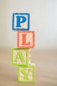 Wooden blocks stacked spelling "PLAY". Wooden blocks are STEM Toys and great for play schemas.