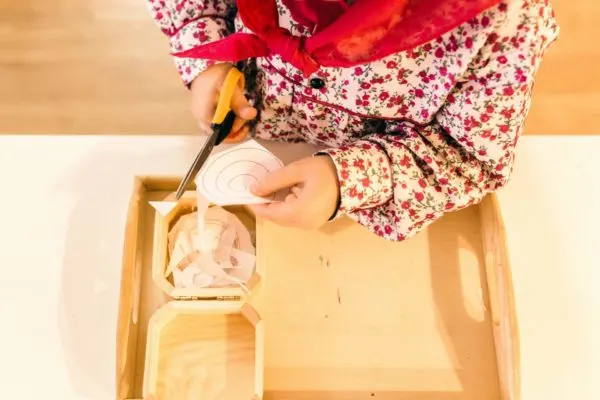 Child cutting paper in Montessori school. Montessori-like schools