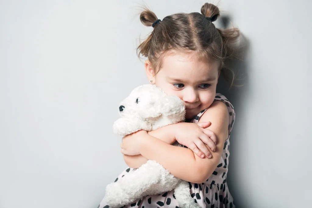 Child Hugging Stuffed Animal.