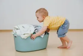 child doing heavy work by pushing laundry basket.