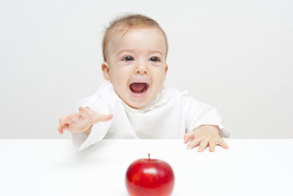 Baby reaching for apple.