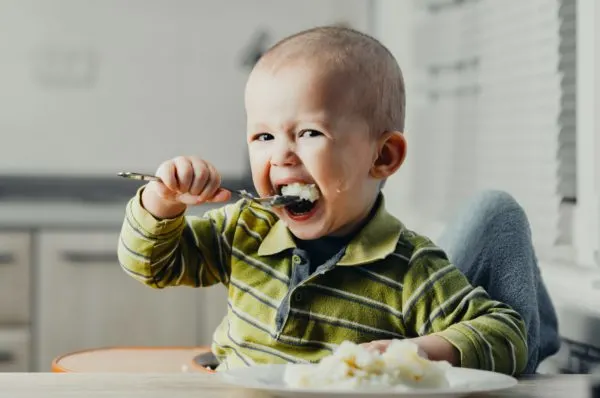 Baby eating with a spoon.