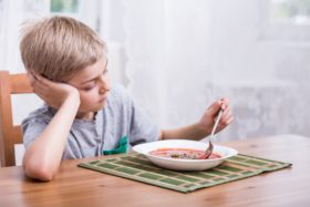 How Picky Eaters Can Eat Healthy image of boy sitting at table with bowl of soup.