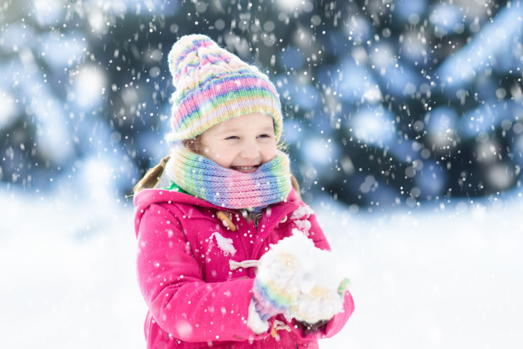 girl outside in snow wearing winter coat.