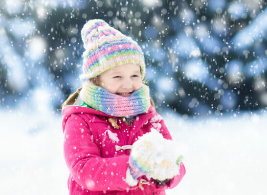 girl outside in snow wearing winter coat.