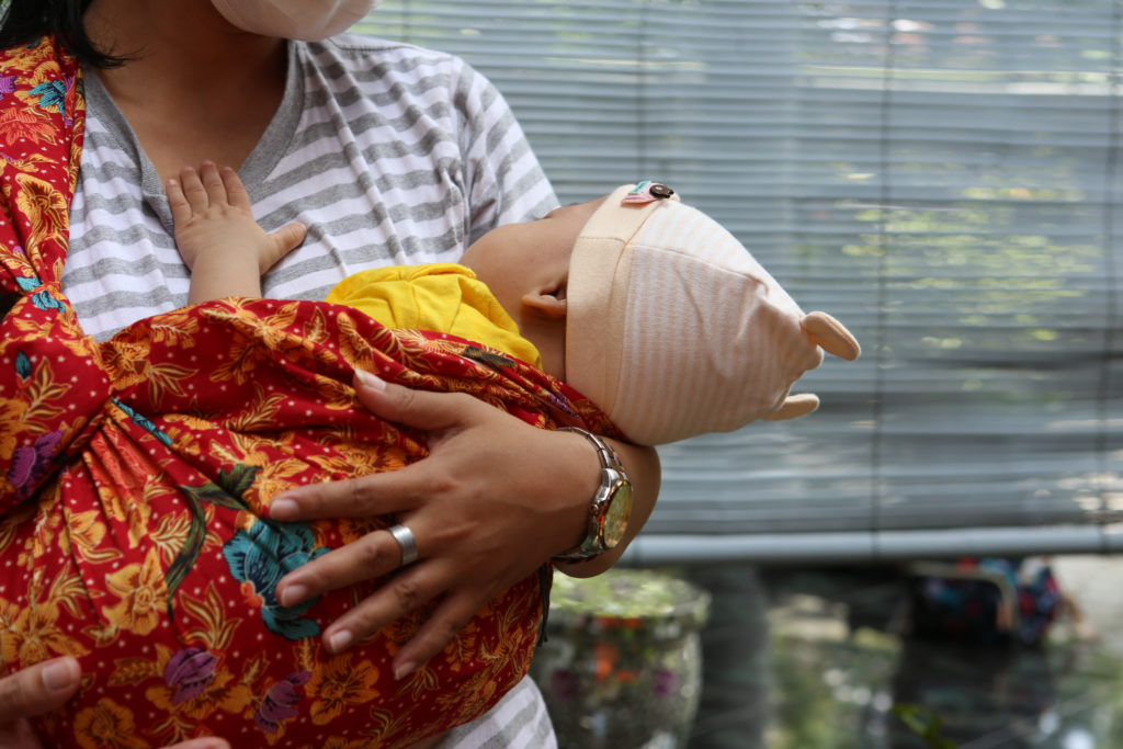 Woman babywearing using sling.