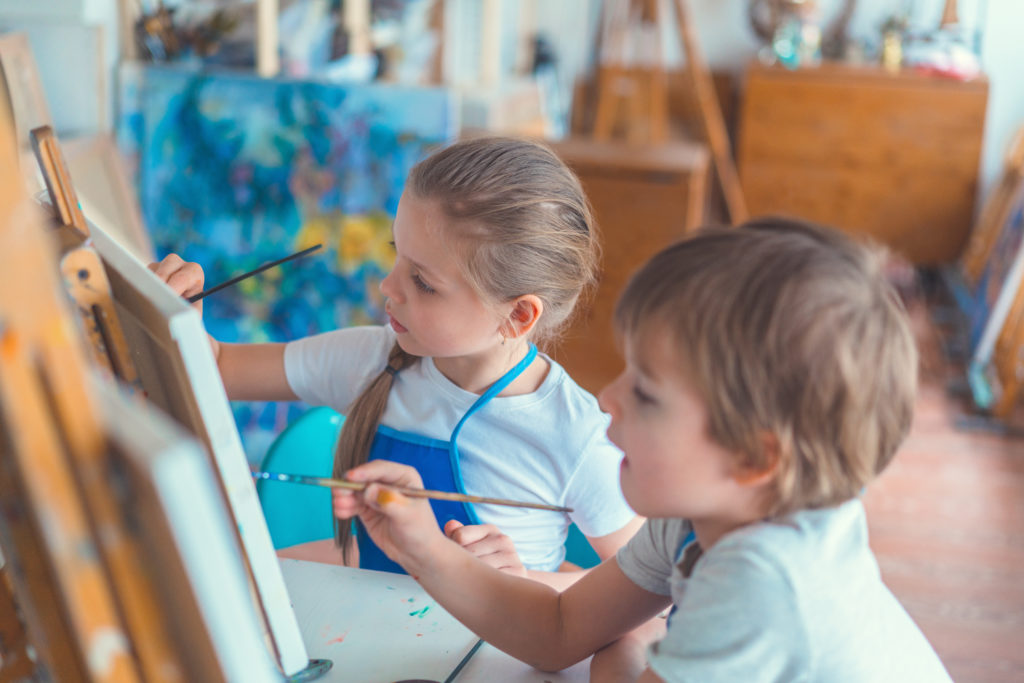children painting on easels in art area for toddlers.