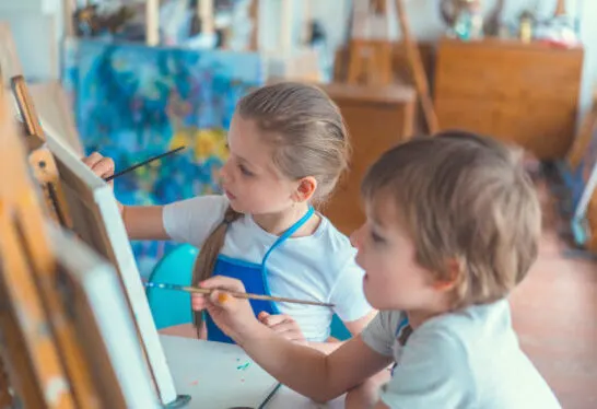 children painting on easels in art area for toddlers.