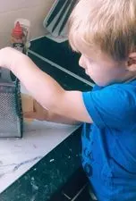 Toddler using cheese grater