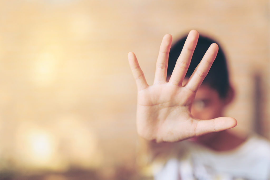 child holding hand up to signal stop.